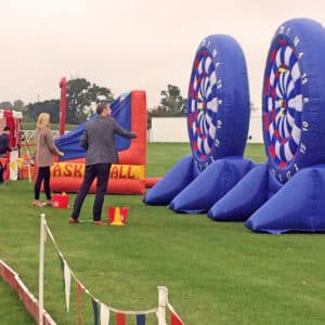 Charity darts game in front of a giant inflatable dart board