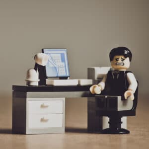 Lego style figure at a desk looking stressed and worried