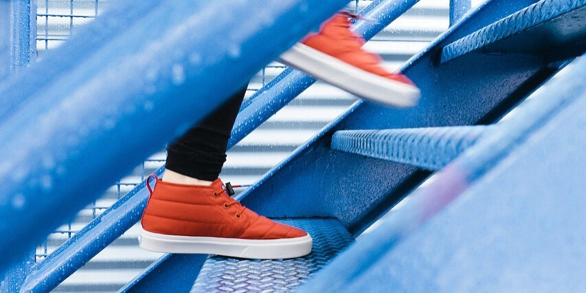 steps Close up on feet walking up blue steps in the rain in red trainers